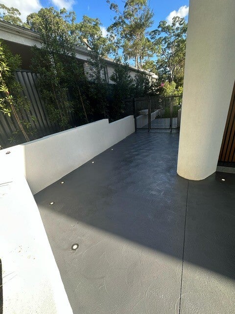 Charcoal spraycrete pathway along a building edge